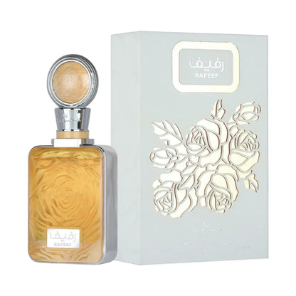 A bottle of Rafeed perfume with amber-colored liquid and a silver cap, displayed next to its light blue-gray packaging box featuring a white rose cutout design.