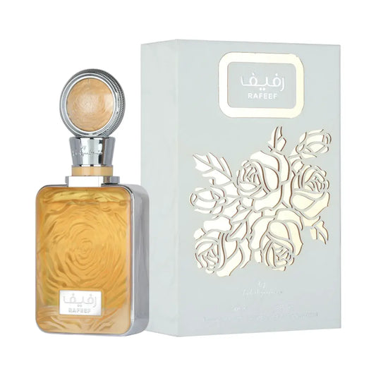 A bottle of Rafeed perfume with amber-colored liquid and a silver cap, displayed next to its light blue-gray packaging box featuring a white rose cutout design.